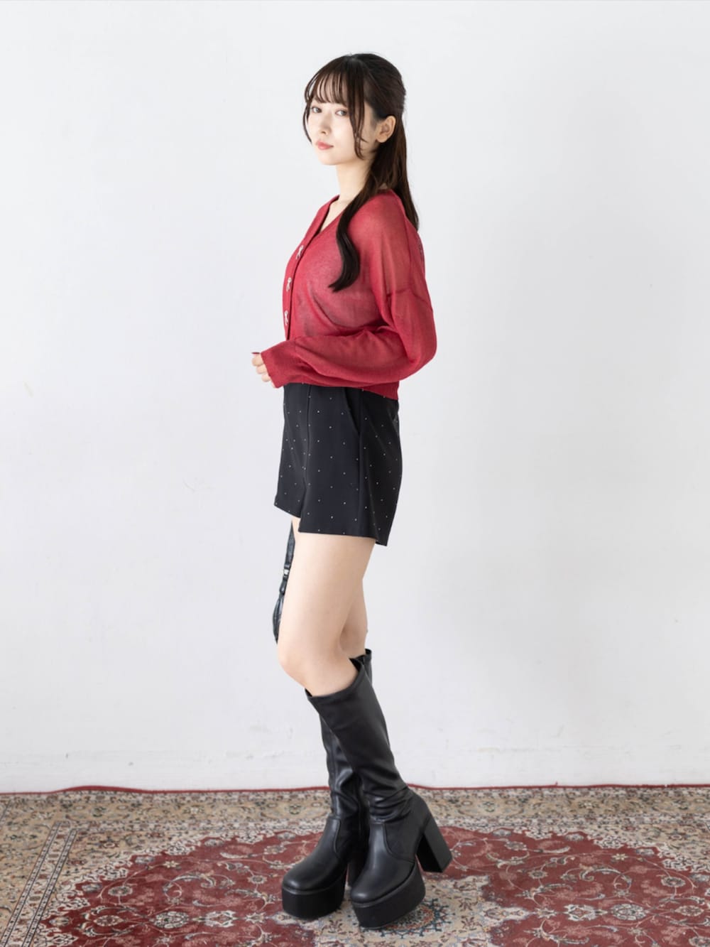 ブラック系のその他パンツ、ブラック系のブーツ、レッド系のカーディガン/ボレロを着用したレディースの秋コーディネートの3枚目の写真