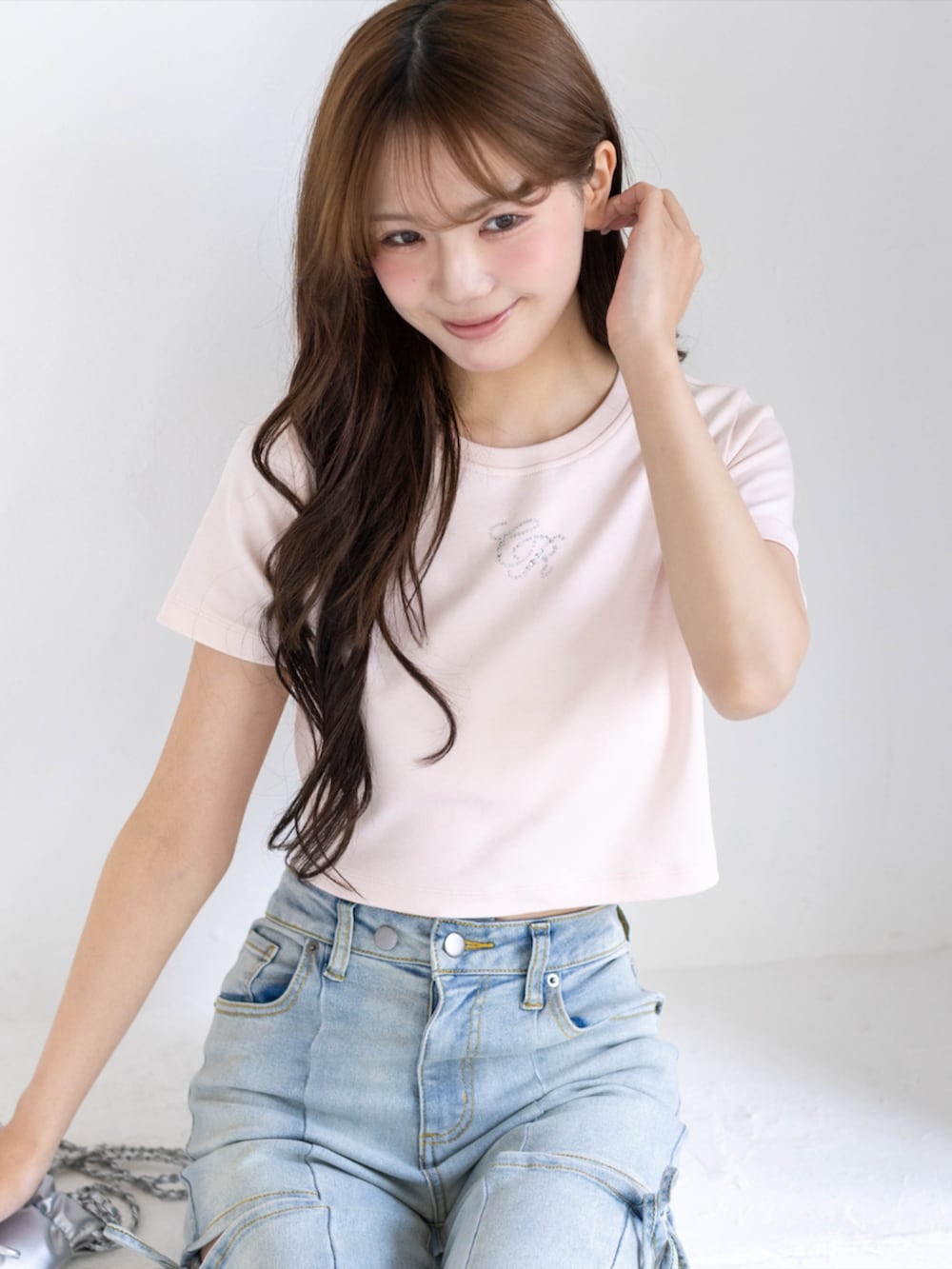 シルバー系のパンプス、ブルー系のデニムパンツ、ホワイト系のショルダーバッグを着用したレディースの夏コーディネートの7枚目の写真
