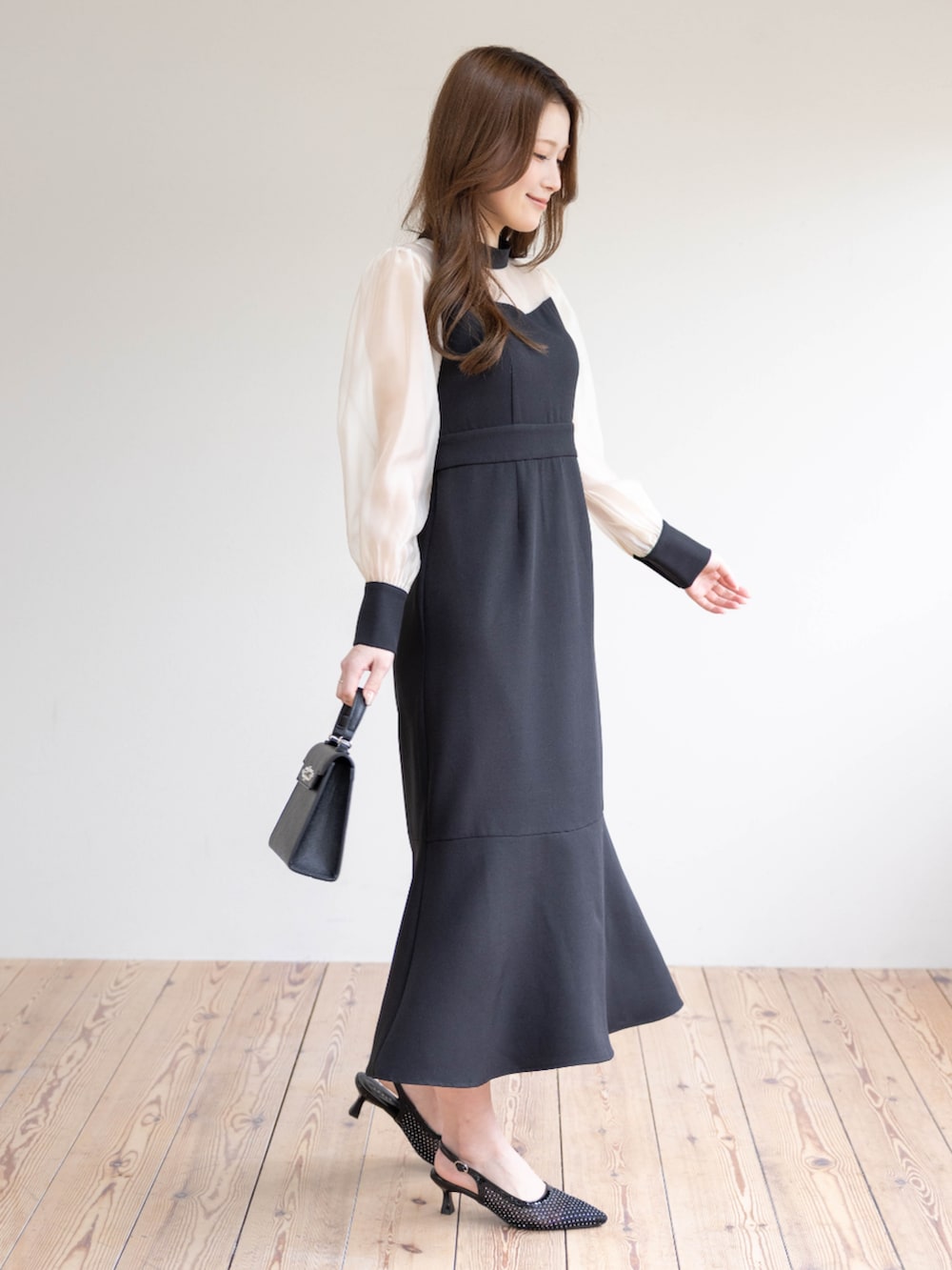 ブラック系のハンドバッグ、ブラック系のパンプス、ブラック系のワンピースを着用したレディースの春コーディネートの3枚目の写真