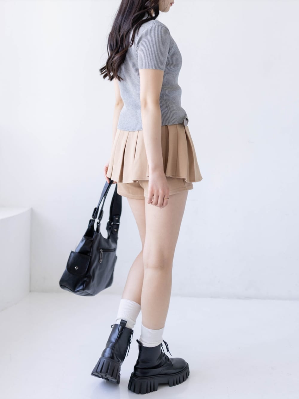 ブラック系のブーツ、ベージュ系のスカート、ブラック系のハンドバッグを着用したレディースの春コーディネートの2枚目の写真