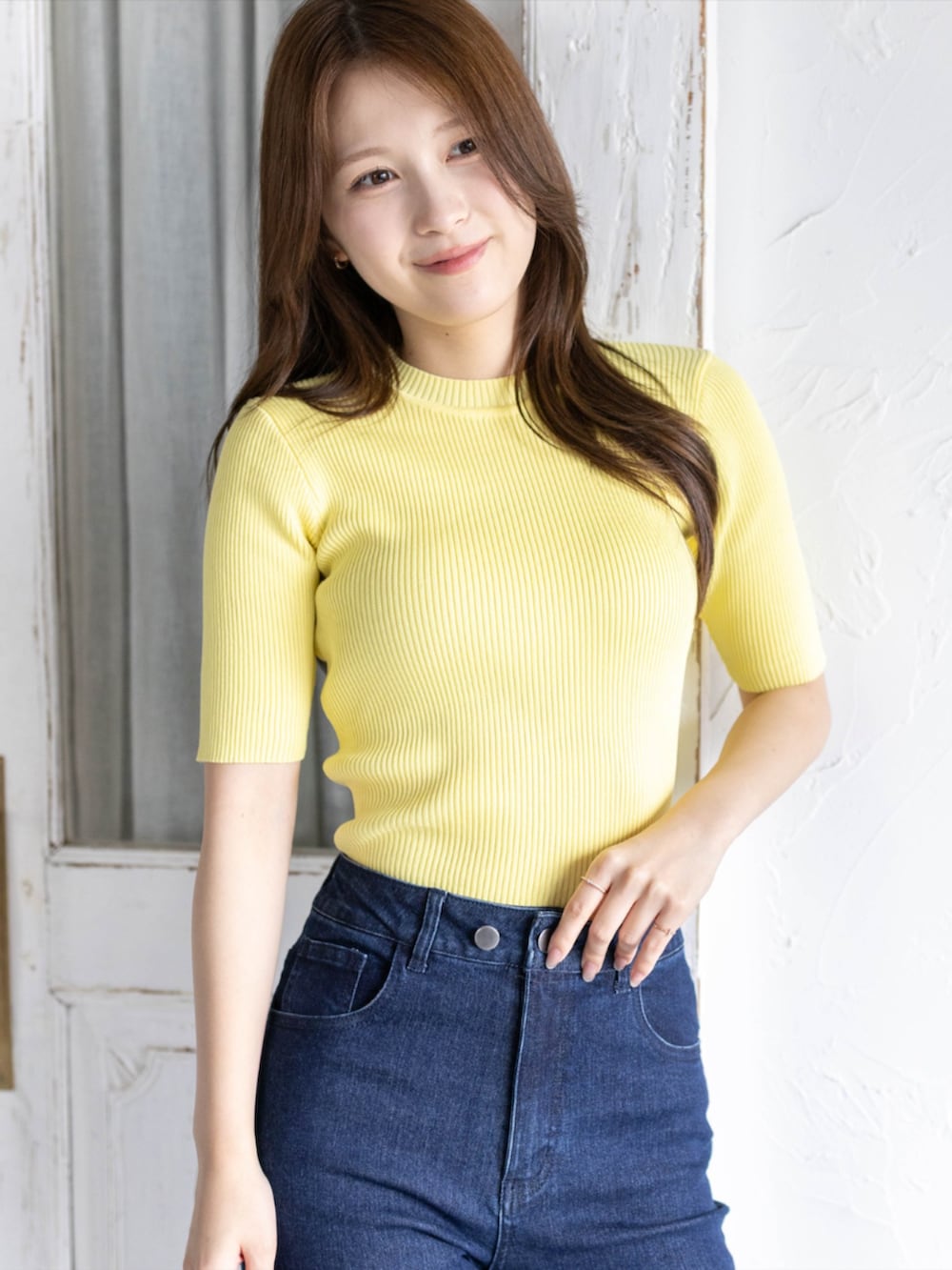 イエロー系のニット/セーター、ホワイト系のパンプス、ブルー系のデニムパンツを着用したレディースの夏コーディネートの3枚目の写真
