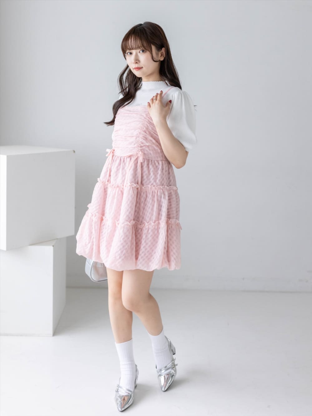 シルバー系のパンプス、ホワイト系のニット/セーター、ピンク系のワンピースを着用したレディースの春コーディネートの2枚目の写真