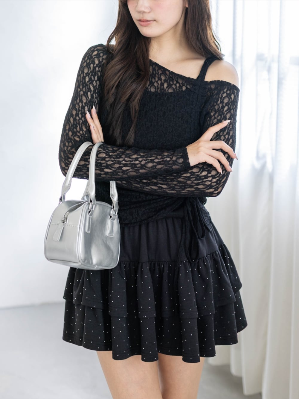 シルバー系のハンドバッグ、ブラック系のアンサンブル、ブラック系のスカートを着用したレディースの春コーディネートの5枚目の写真
