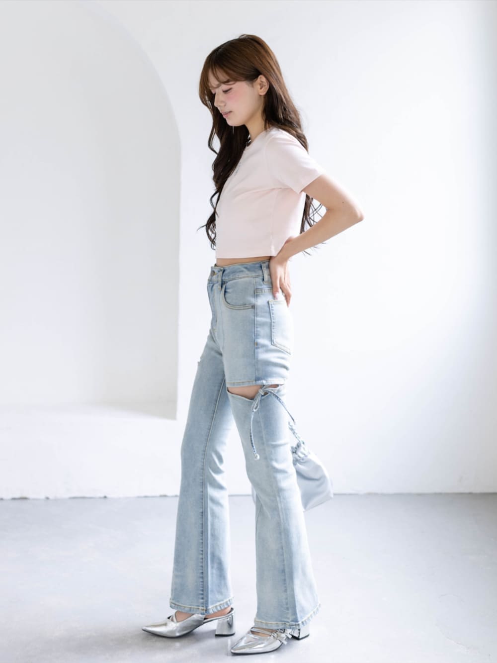 シルバー系のパンプス、ブルー系のデニムパンツ、ホワイト系のショルダーバッグを着用したレディースの夏コーディネートの2枚目の写真