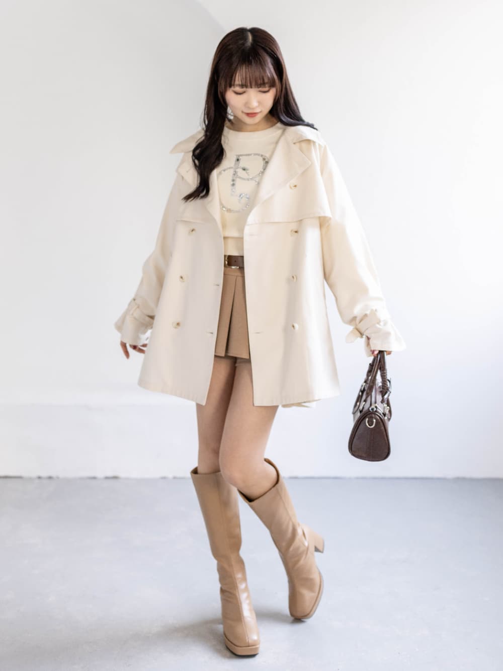 ベージュ系のブーツ、ホワイト系のトレンチコート、ホワイト系のニット/セーターを着用したレディースの春コーディネートの4枚目の写真