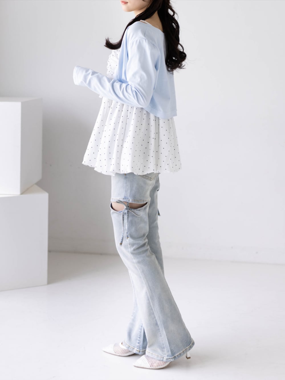 ホワイト系のチュニック、ホワイト系のパンプス、ブルー系のデニムパンツを着用したレディースの夏コーディネートの3枚目の写真