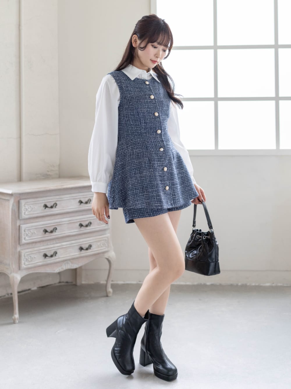 ブルー系のチュニック、ブラック系のハンドバッグ、ホワイト系のシャツ/ブラウスを着用したレディースの春コーディネートの2枚目の写真