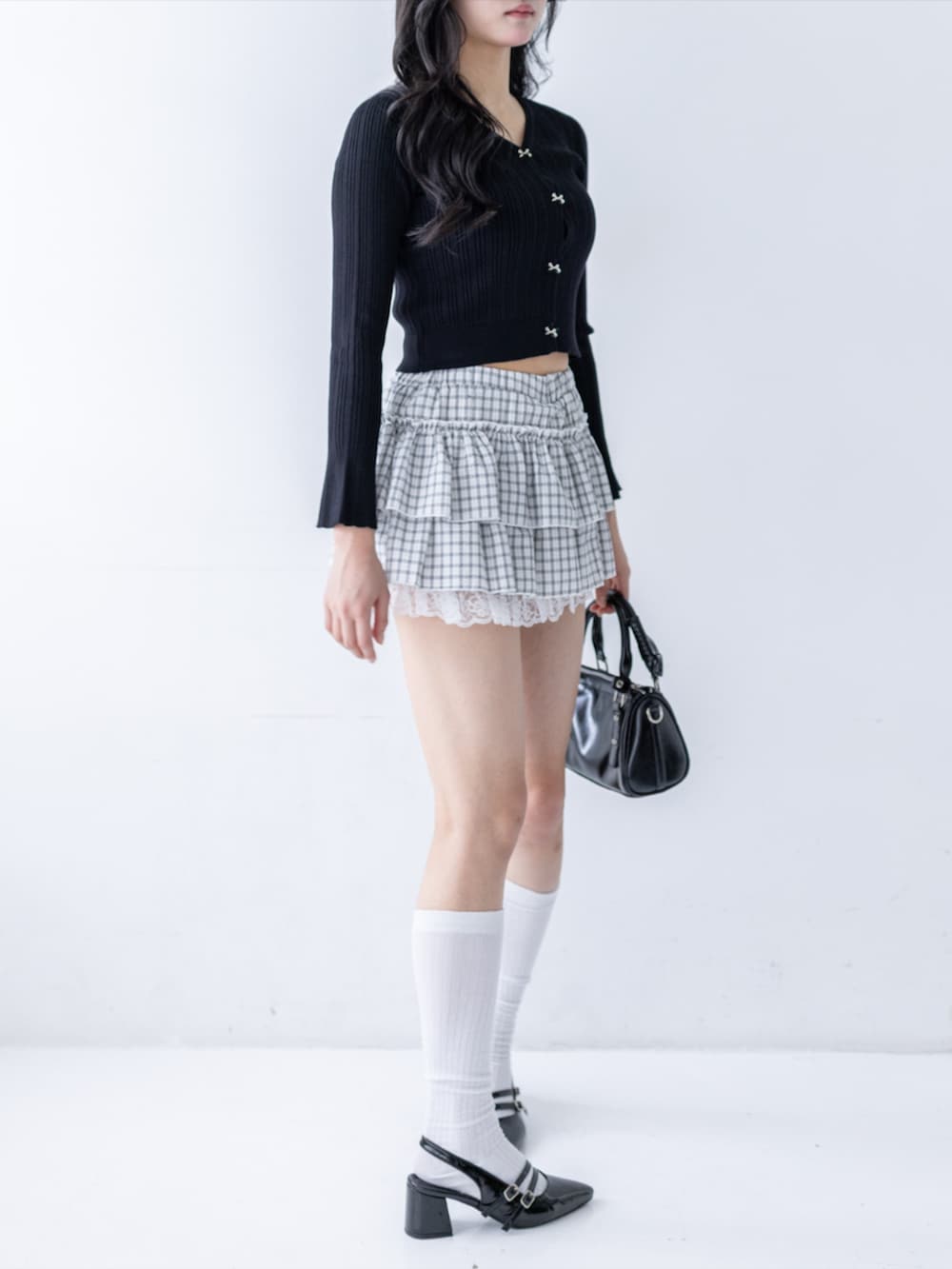 ブラック系のパンプス、ブラック系のハンドバッグ、ホワイト系のスカートを着用したレディースの夏コーディネートの4枚目の写真