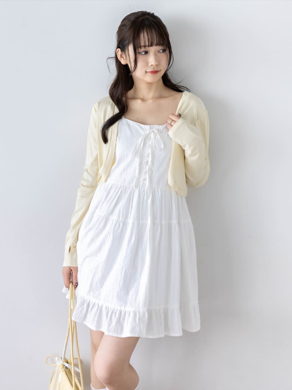 ホワイト系のワンピース、ホワイト系のパンプス、イエロー系のカーディガン/ボレロを着用したレディースの夏コーディネートの5枚目の写真
