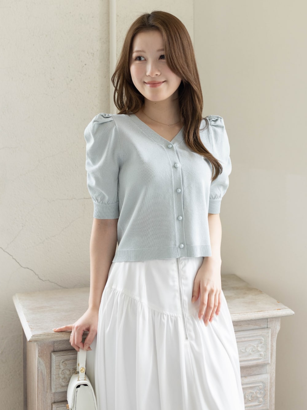 ホワイト系のスカート、ホワイト系のパンプス、グレー系のカーディガン/ボレロを着用したレディースの春コーディネートの6枚目の写真