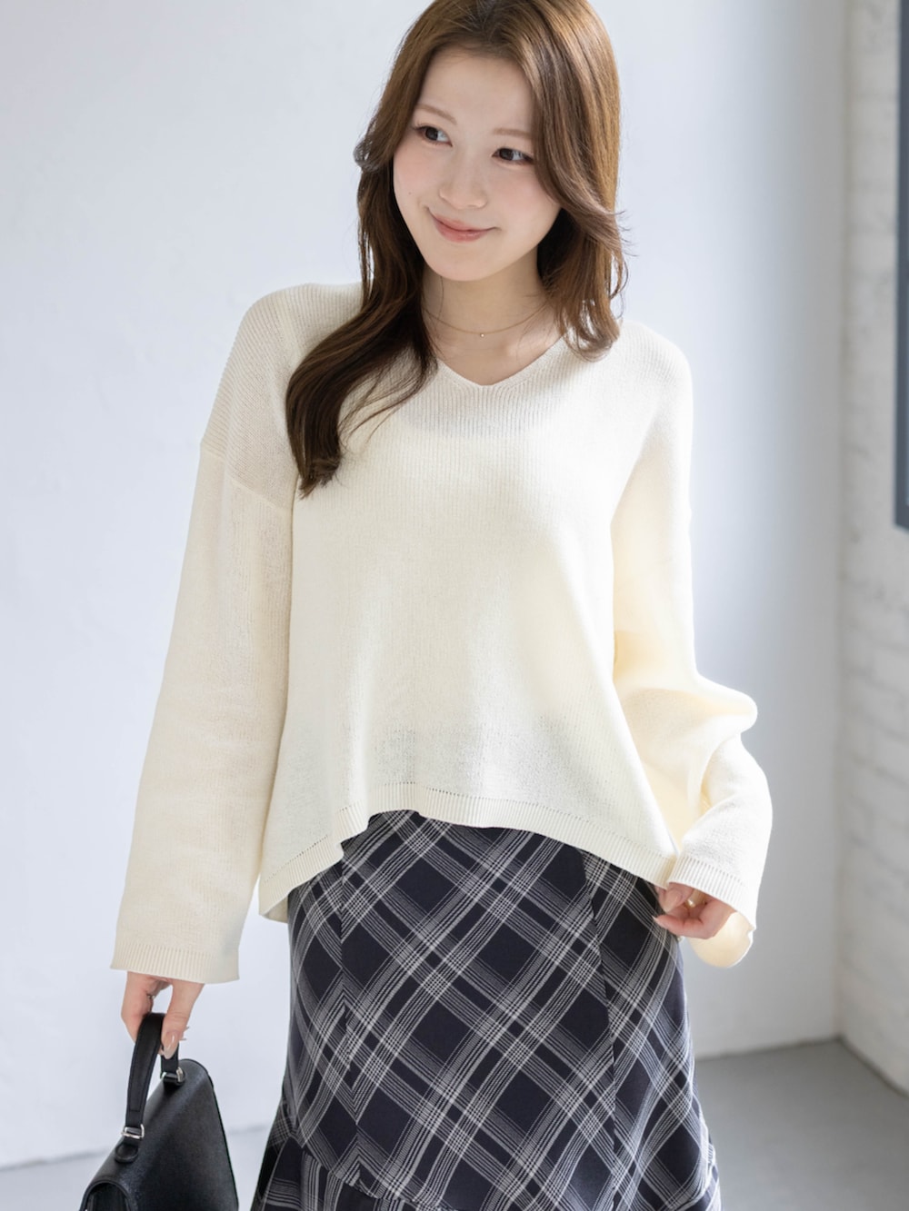 ブラック系のパンプス、ホワイト系のニット/セーター、ブラック系のスカートを着用したレディースの春コーディネートの4枚目の写真