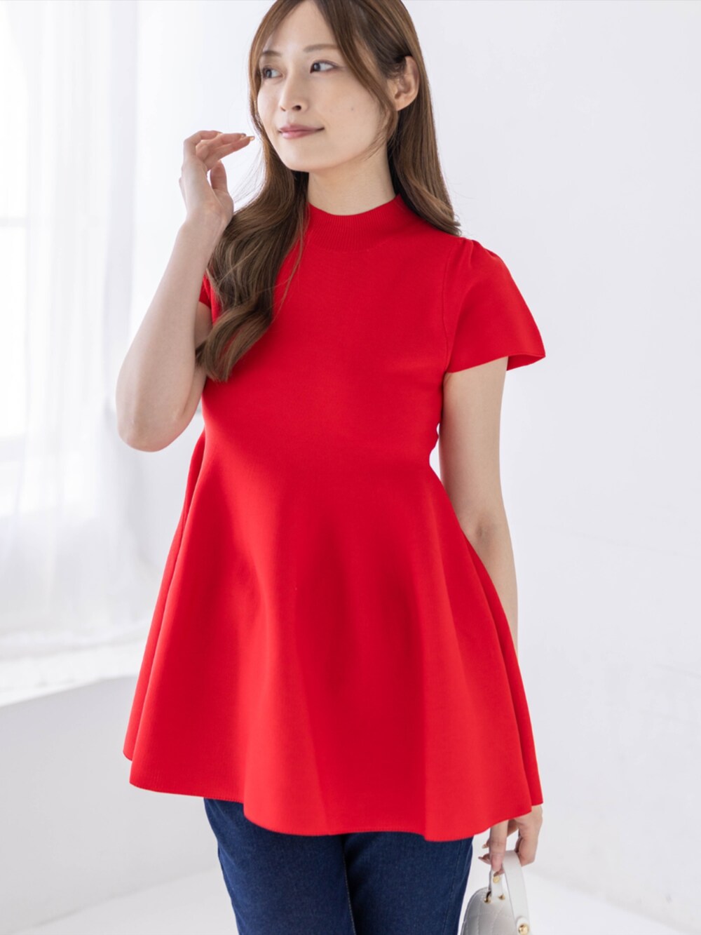 ブルー系のデニムパンツ、ホワイト系のパンプス、レッド系のニット/セーターを着用したレディースの春コーディネートの3枚目の写真