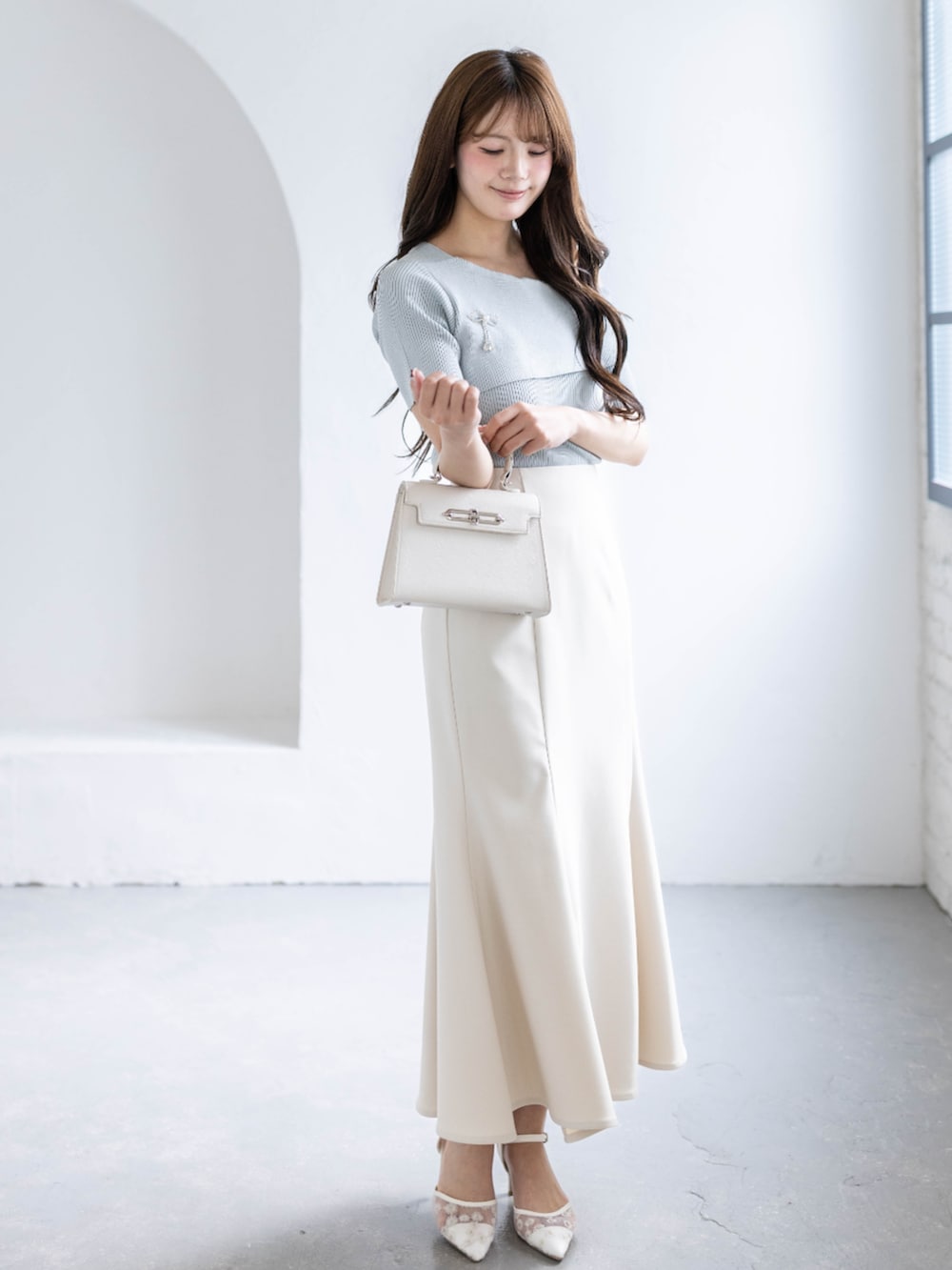 ホワイト系のスカート、ホワイト系のハンドバッグ、グレー系のニット/セーターを着用したレディースの春コーディネートの2枚目の写真