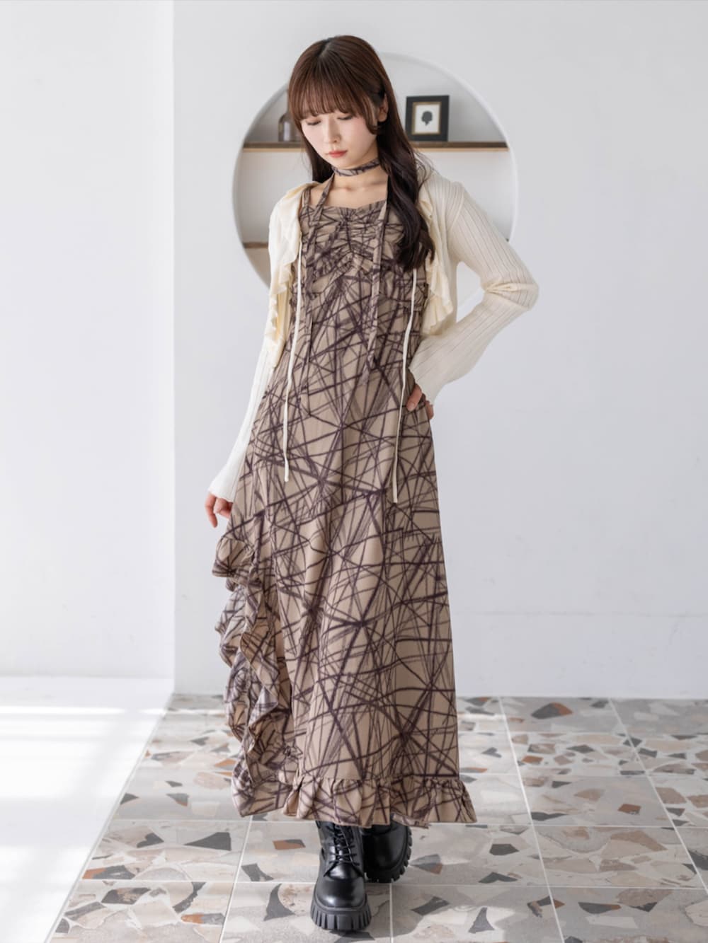 ブラック系のブーツ、ホワイト系のカーディガン/ボレロ、ベージュ系のワンピースを着用したレディースの春コーディネートの2枚目の写真