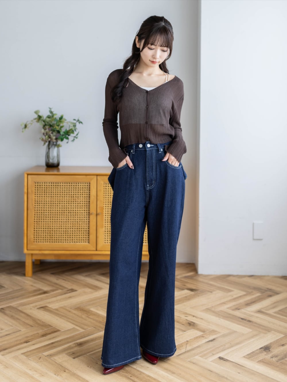 レッド系のパンプス、ブラウン系のカーディガン/ボレロ、ブルー系のデニムパンツを着用したレディースの夏コーディネートの2枚目の写真
