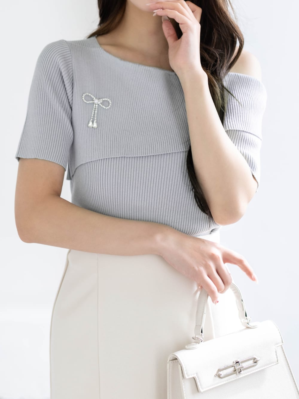 ホワイト系のスカート、ホワイト系のハンドバッグ、グレー系のニット/セーターを着用したレディースの春コーディネートの6枚目の写真