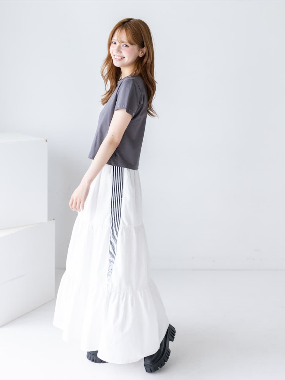 ブラック系のブーツ、ホワイト系のスカート、グレー系のTシャツ/カットソーを着用したレディースの夏コーディネートの3枚目の写真