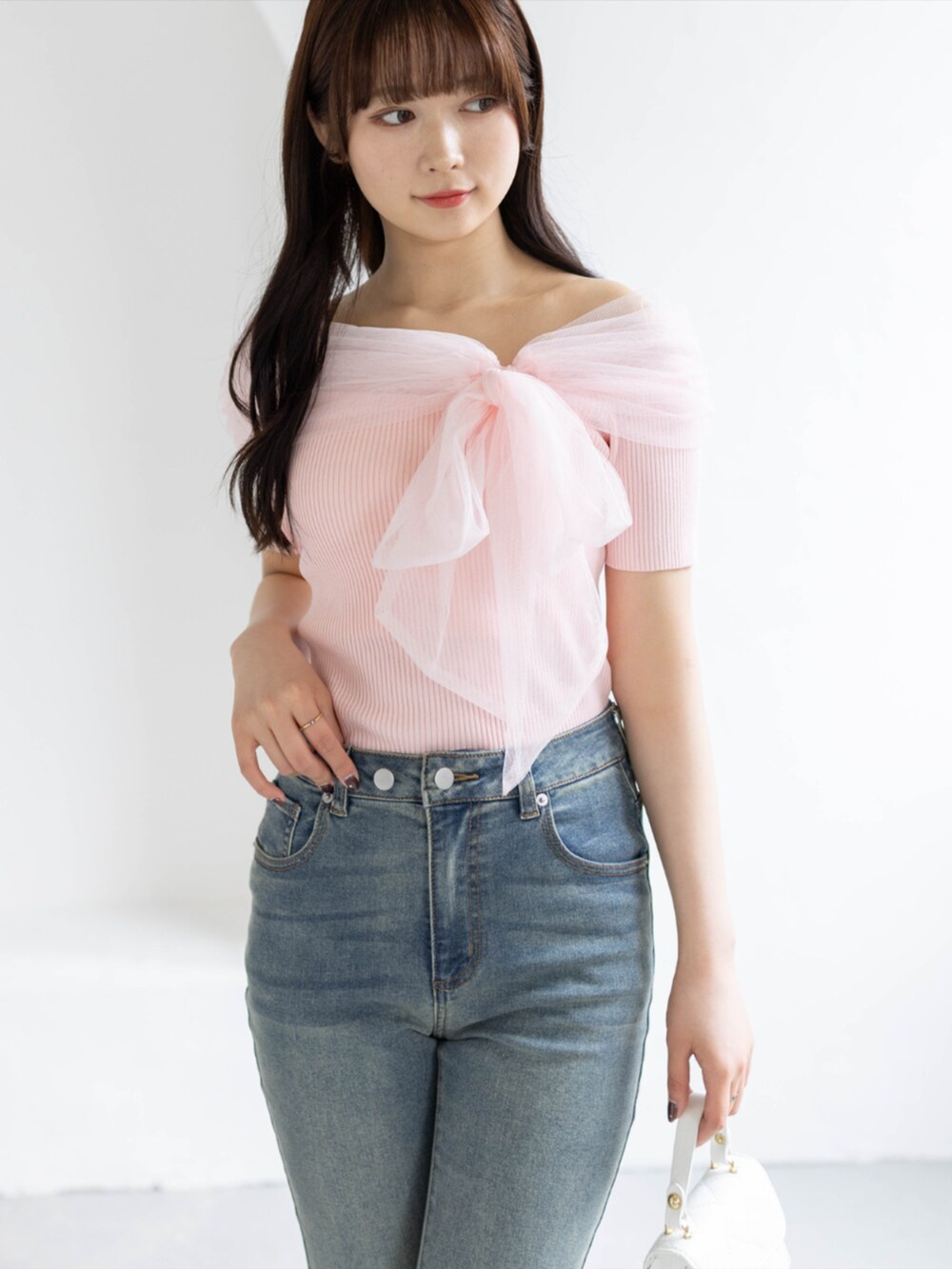 ブルー系のデニムパンツ、ホワイト系のショルダーバッグ、ホワイト系のパンプスを着用したレディースの春コーディネートの2枚目の写真