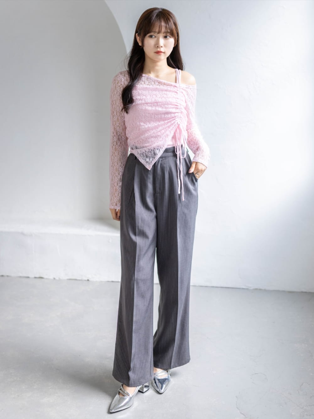 シルバー系のパンプス、グレー系のスラックス、ピンク系のアンサンブルを着用したレディースの春コーディネートの3枚目の写真