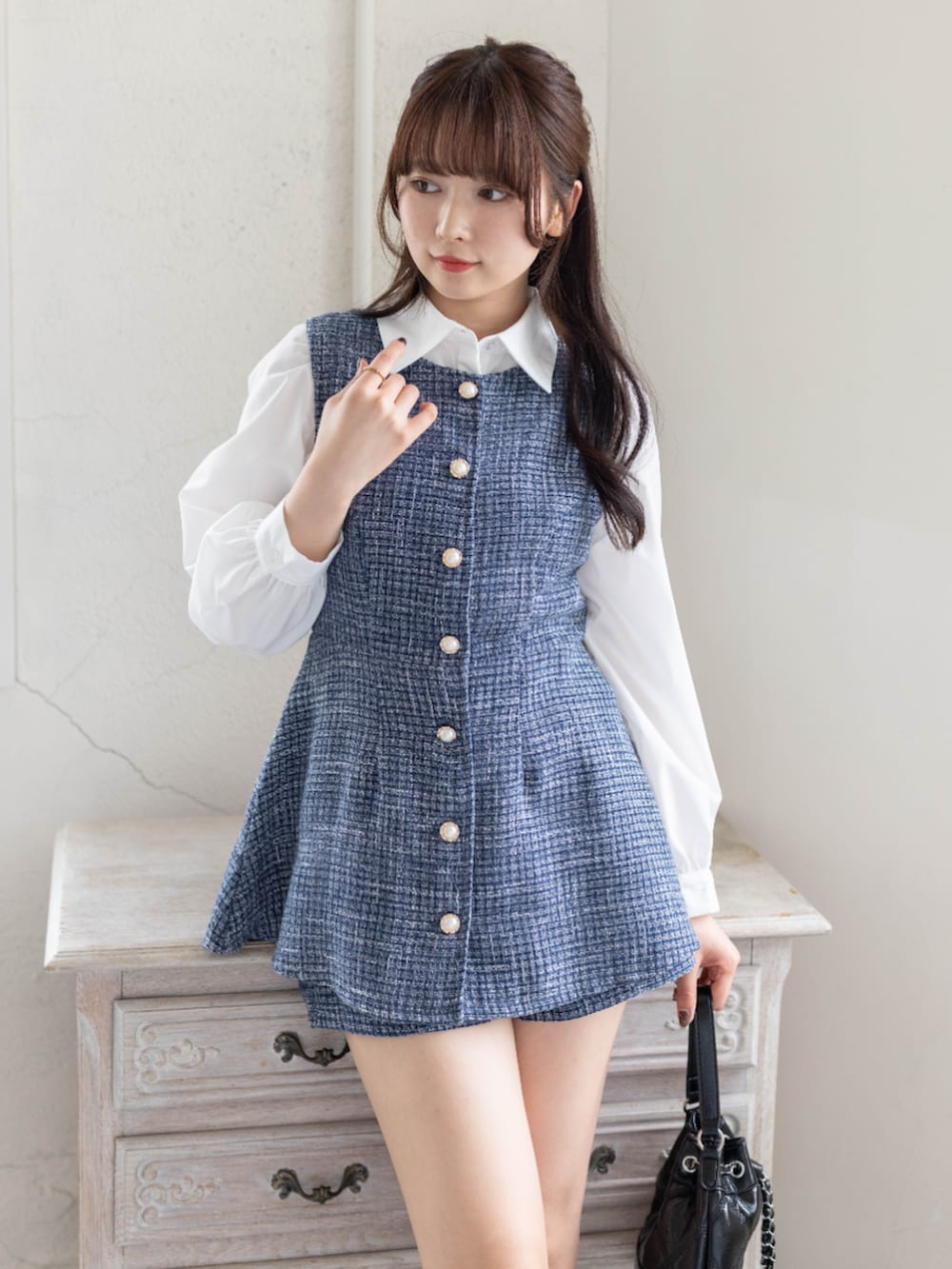 ブルー系のチュニック、ブラック系のハンドバッグ、ホワイト系のシャツ/ブラウスを着用したレディースの春コーディネートの4枚目の写真