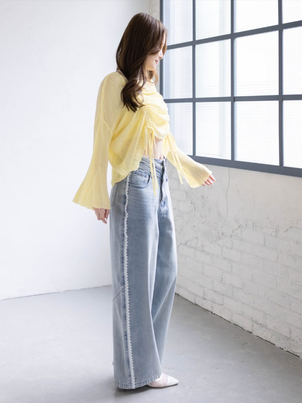 ブルー系のデニムパンツ、ホワイト系のパンプス、イエロー系のニット/セーターを着用したレディースの春コーディネートの2枚目の写真