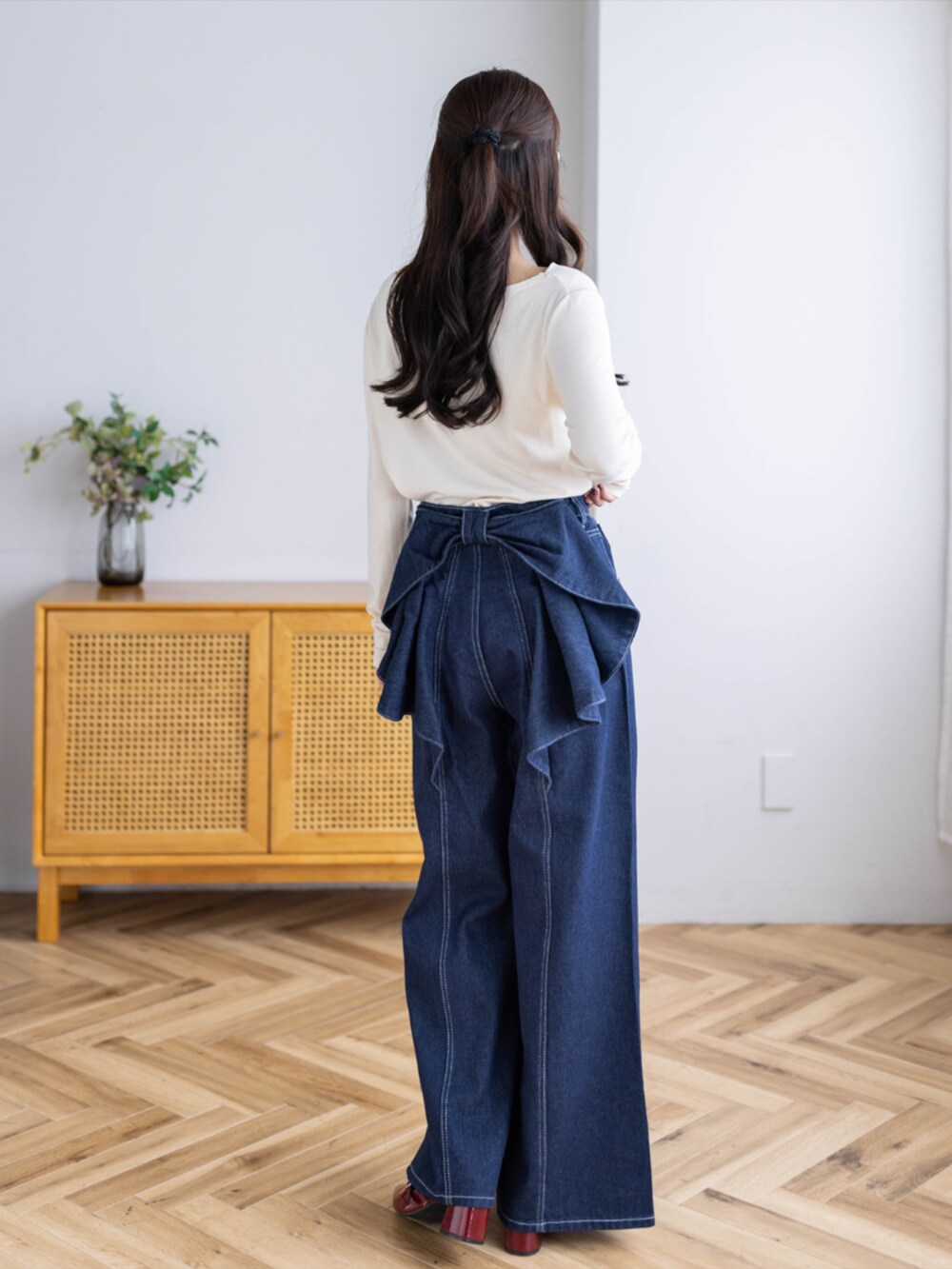 レッド系のパンプス、ブルー系のデニムパンツ、ホワイト系のTシャツ/カットソーを着用したレディースの秋コーディネートの2枚目の写真
