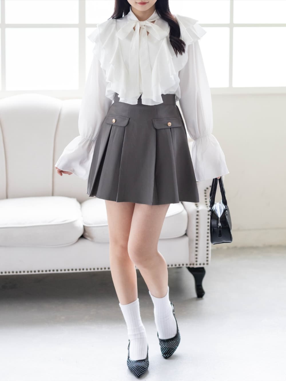 ブラック系のパンプス、グレー系のスカート、ホワイト系のシャツ/ブラウスを着用したレディースの夏コーディネートの2枚目の写真