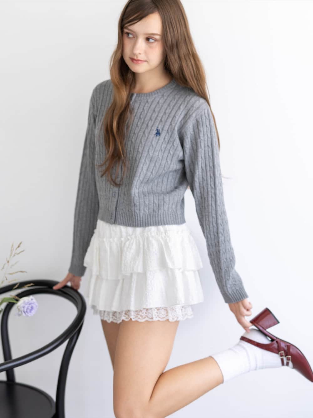 レッド系のパンプス、グレー系のカーディガン/ボレロ、ホワイト系のスカートを着用したレディースの秋コーディネートの9枚目の写真