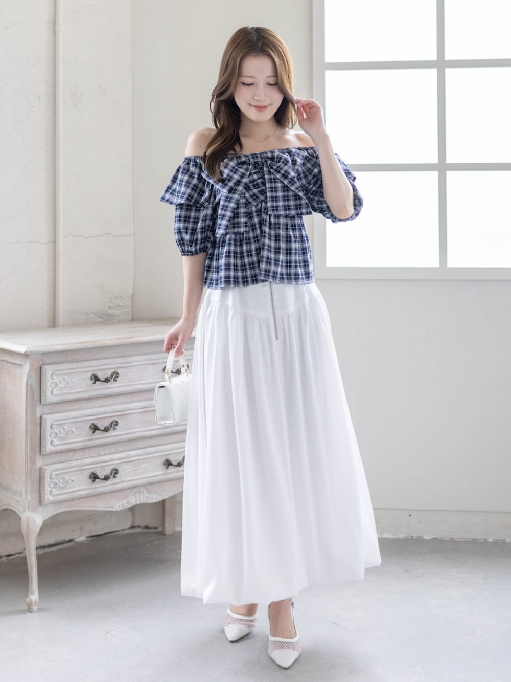 ホワイト系のスカート、ホワイト系のパンプス、ブルー系のシャツ/ブラウスを着用したレディースの春コーディネートの2枚目の写真