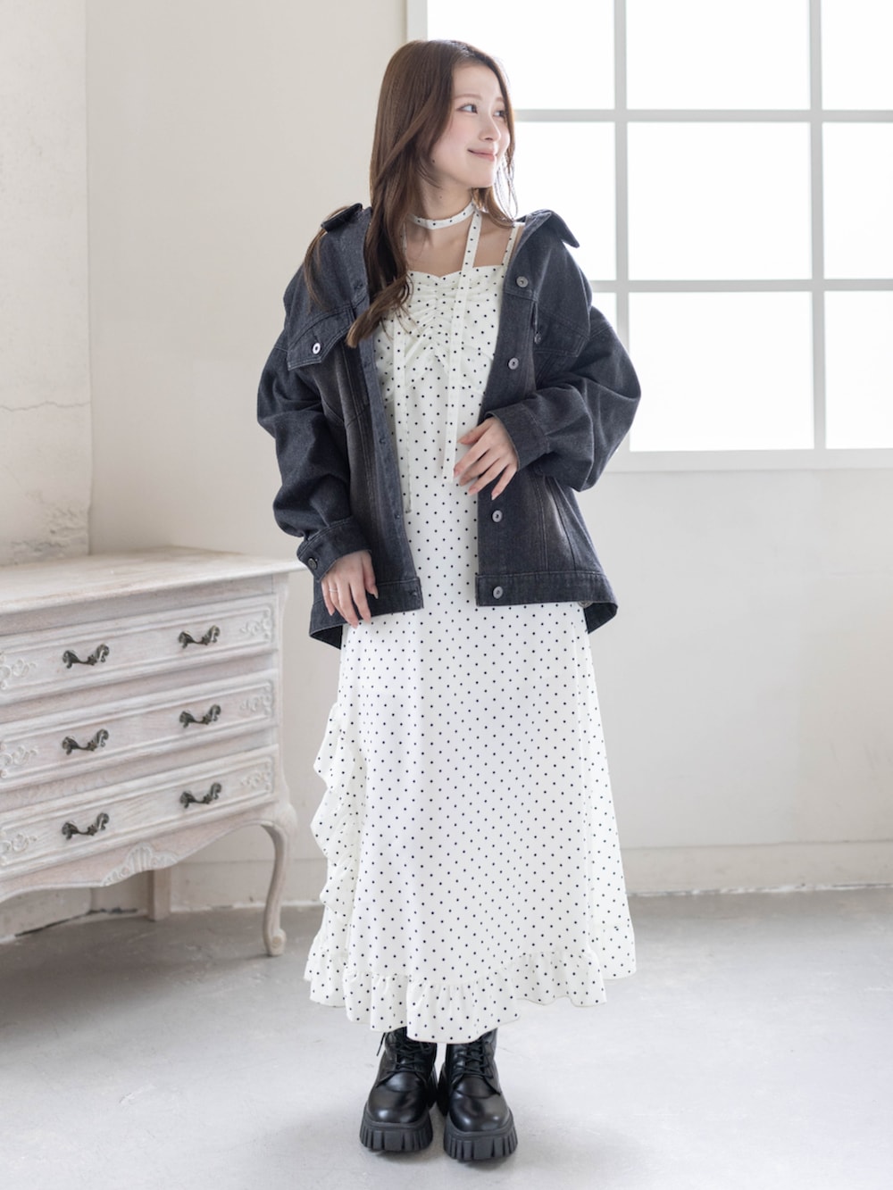 ブラック系のブーツ、ブラック系のデニムジャケット、ホワイト系のワンピースを着用したレディースの春コーディネートの4枚目の写真