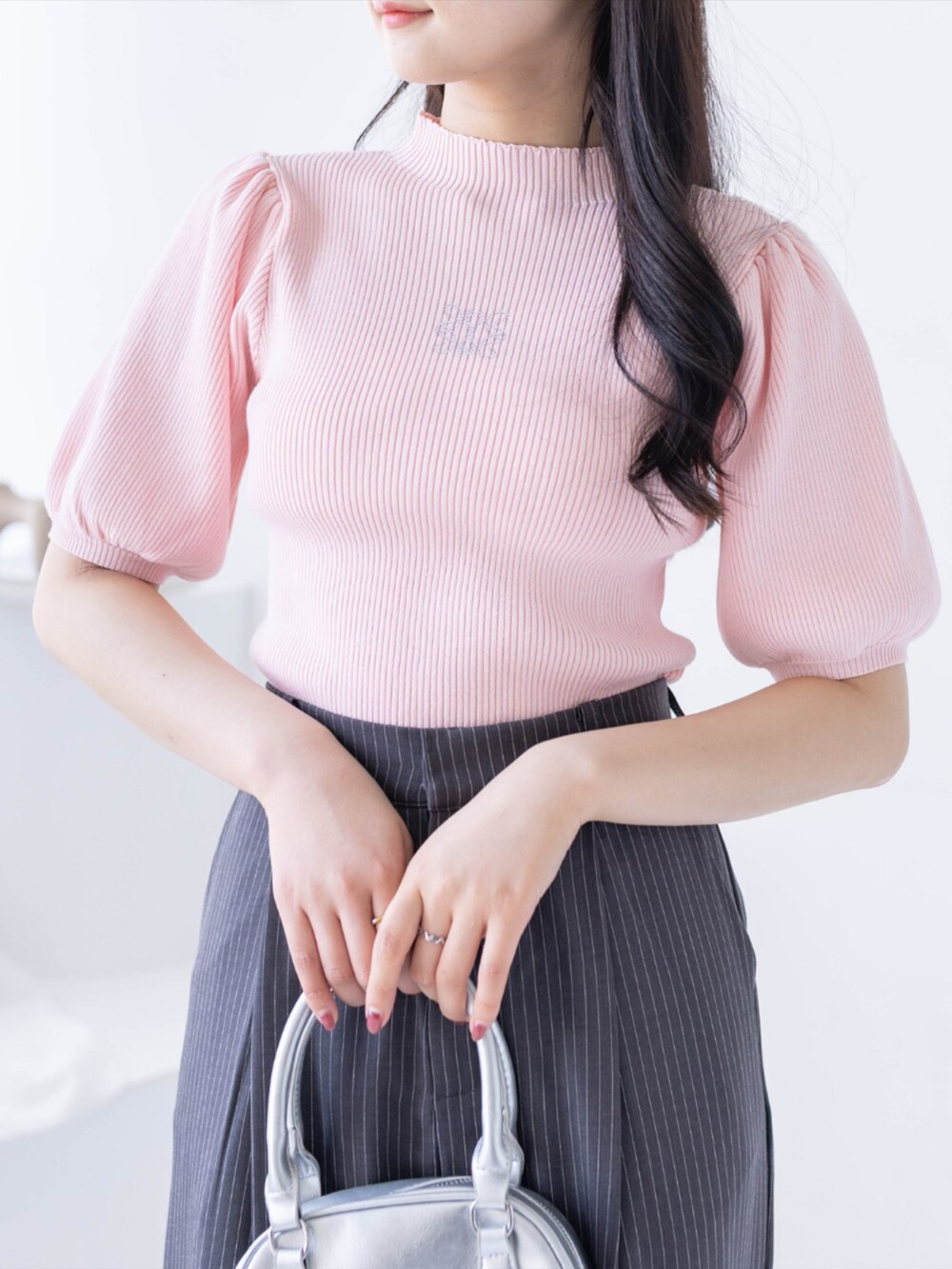 シルバー系のパンプス、グレー系のスラックス、ピンク系のニット/セーターを着用したレディースの春コーディネートの3枚目の写真