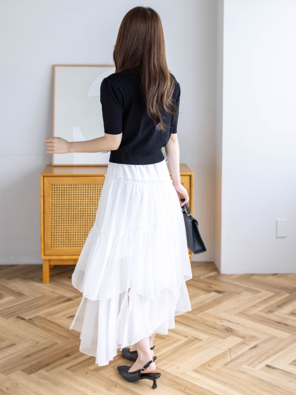 ブラック系のハンドバッグ、ブラック系のパンプス、ホワイト系のスカートを着用したレディースの夏コーディネートの3枚目の写真
