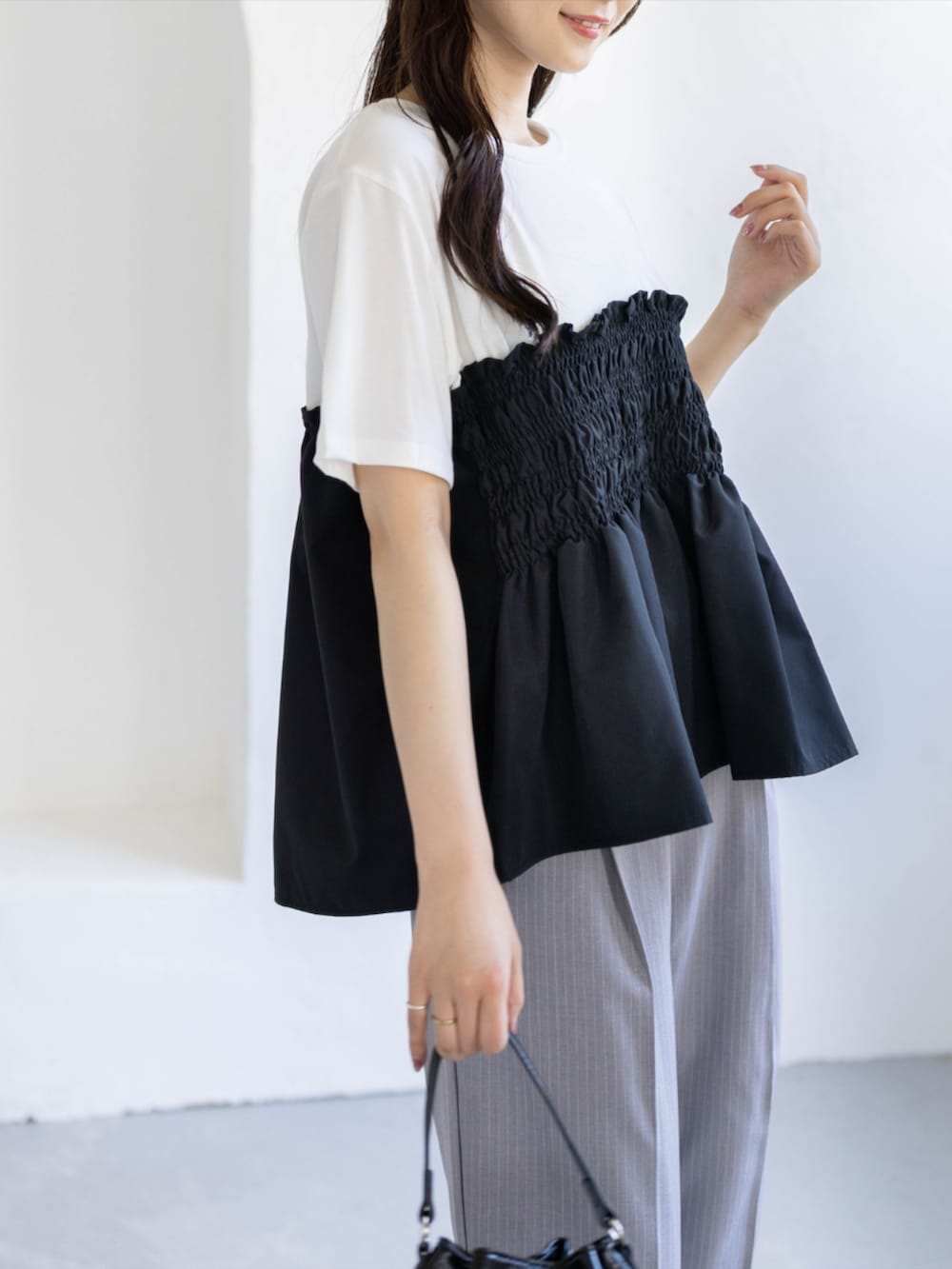 ブラック系のパンプス、グレー系のスラックス、ブラック系のハンドバッグを着用したレディースの夏コーディネートの8枚目の写真