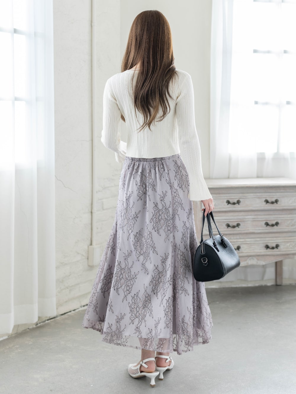 ホワイト系のカーディガン/ボレロ、グレー系のスカートを着用したレディースの冬コーディネートの2枚目の写真