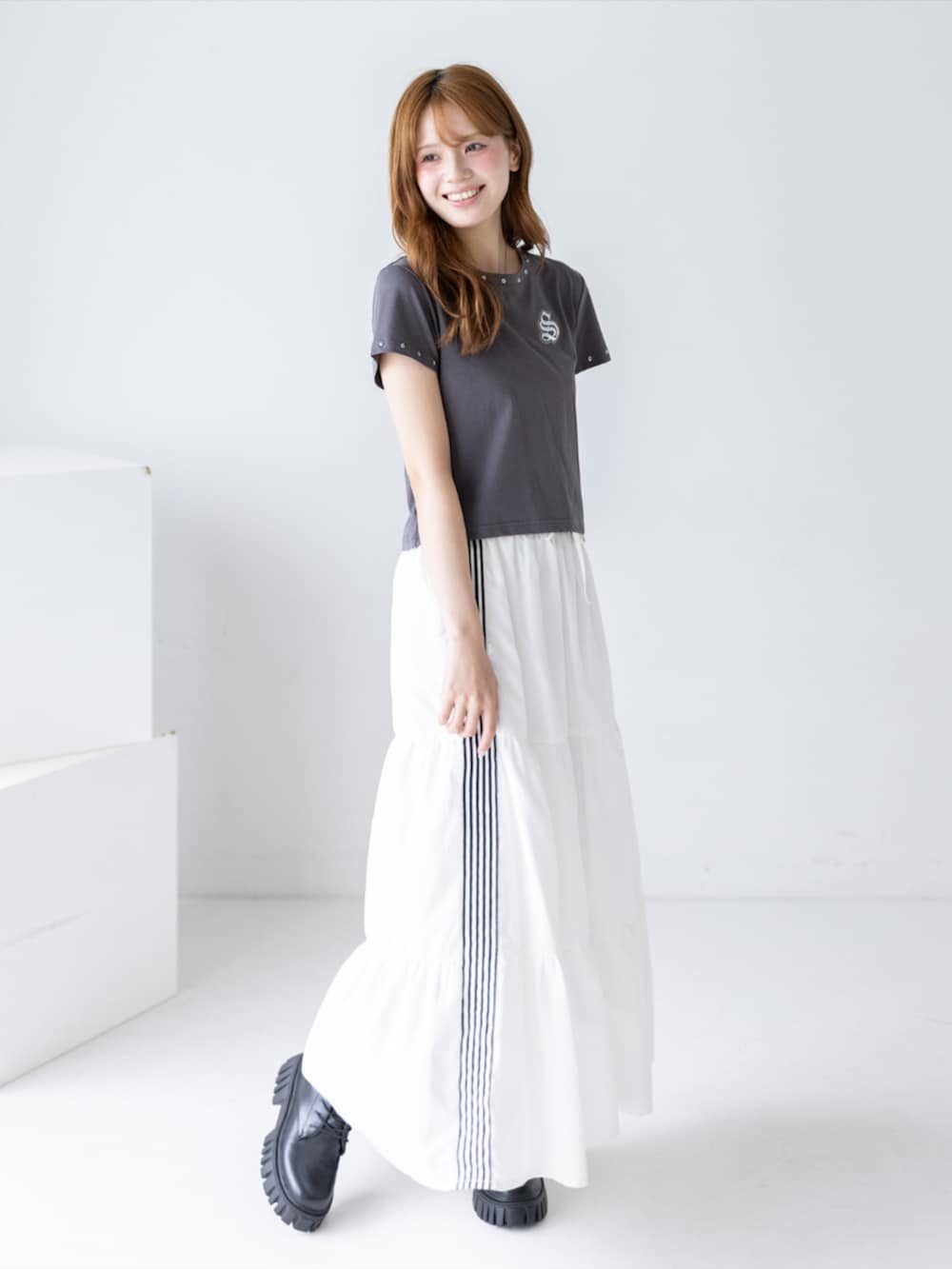 ブラック系のブーツ、ホワイト系のスカート、グレー系のTシャツ/カットソーを着用したレディースの夏コーディネートの2枚目の写真