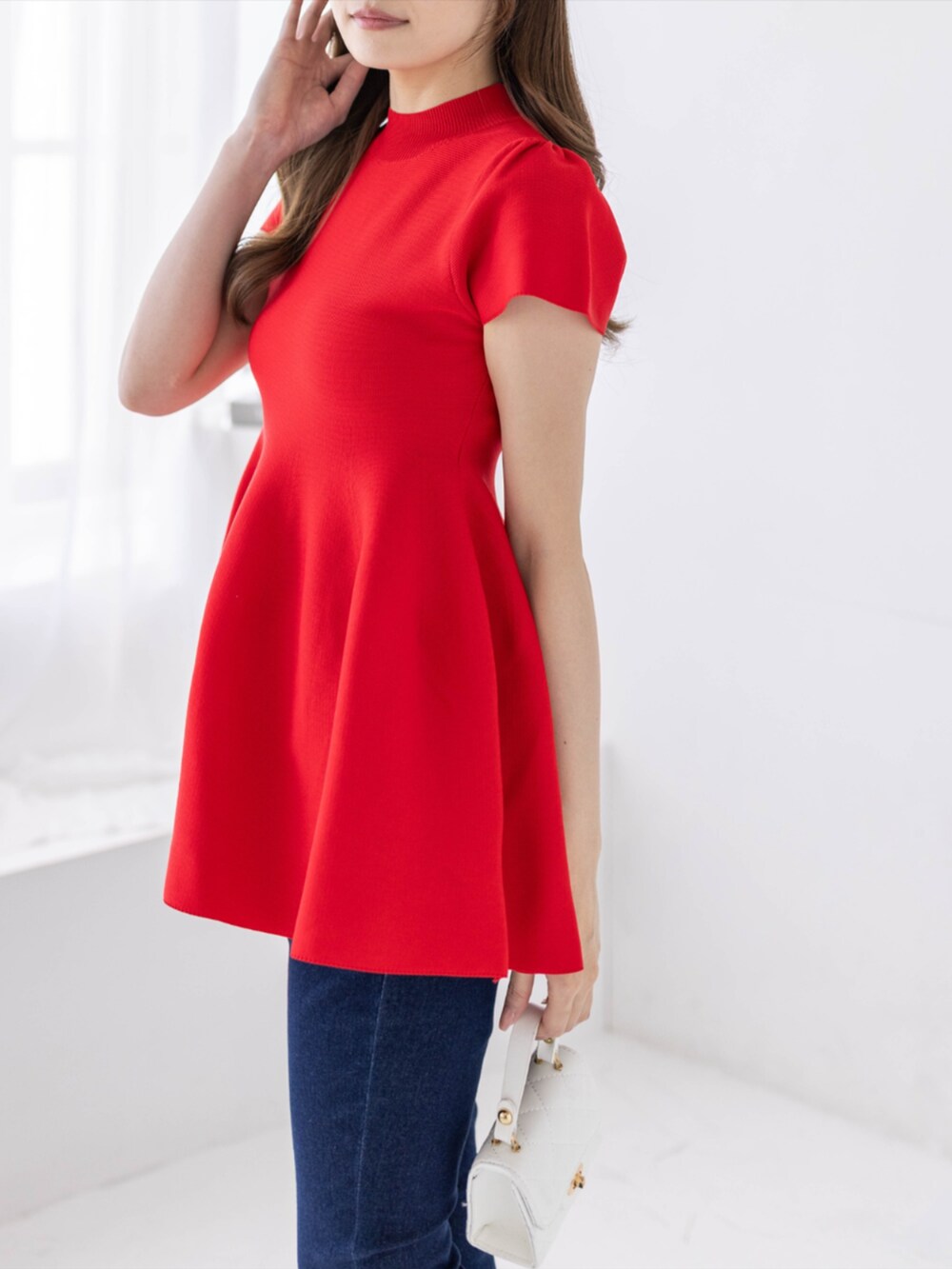 ブルー系のデニムパンツ、ホワイト系のパンプス、レッド系のニット/セーターを着用したレディースの春コーディネートの4枚目の写真