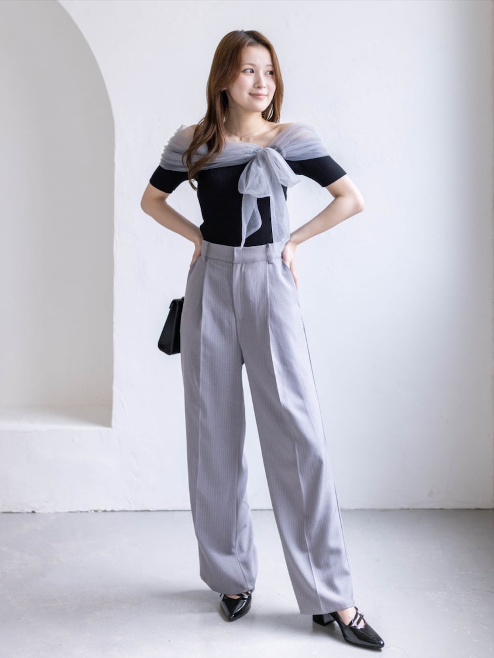 ブラック系のパンプス、ブラック系のニット/セーター、グレー系のスラックスを着用したレディースの春コーディネートの2枚目の写真