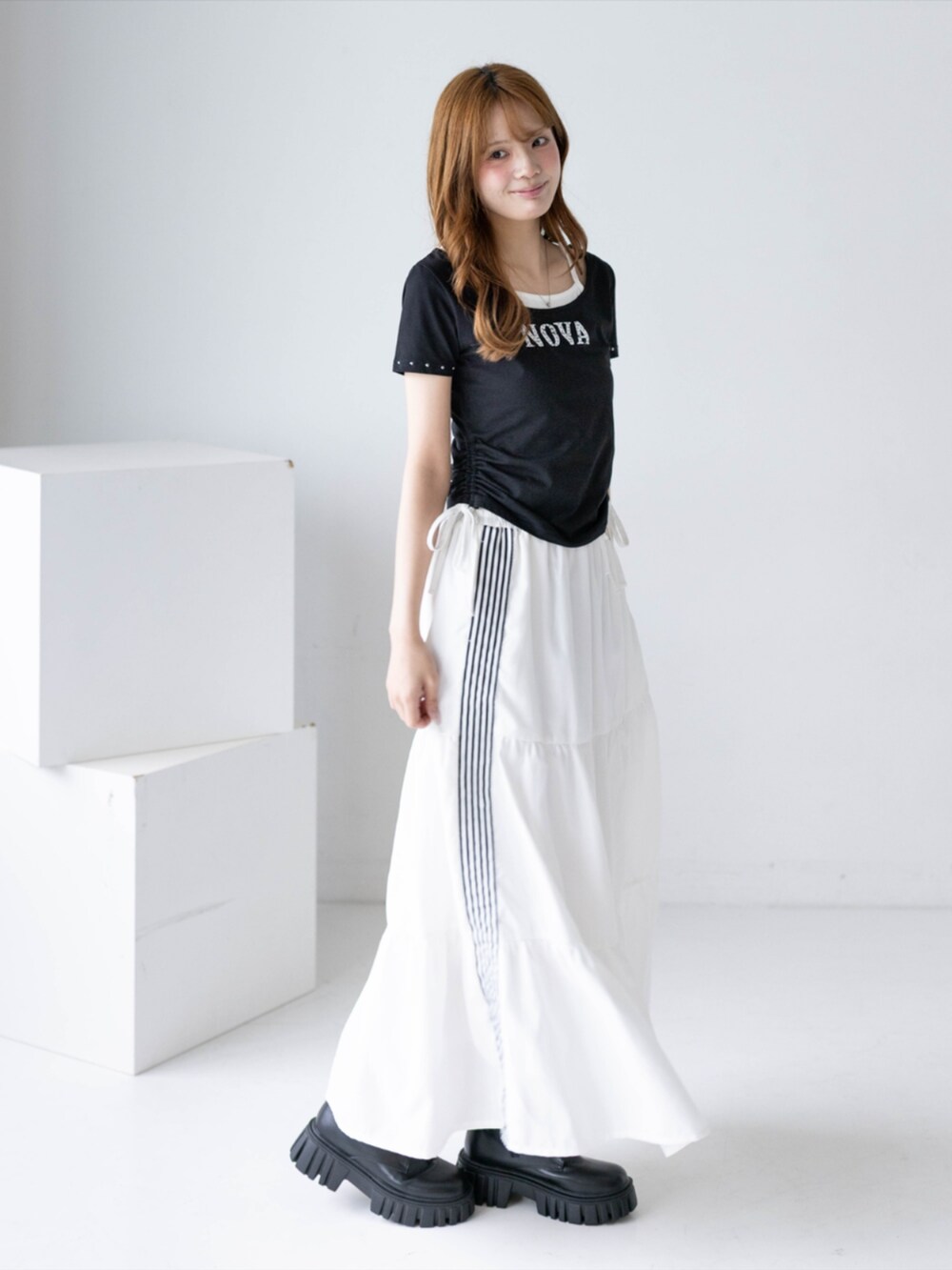 ブラック系のブーツ、ホワイト系のスカート、ブラック系のTシャツ/カットソーを着用したレディースの夏コーディネートの4枚目の写真