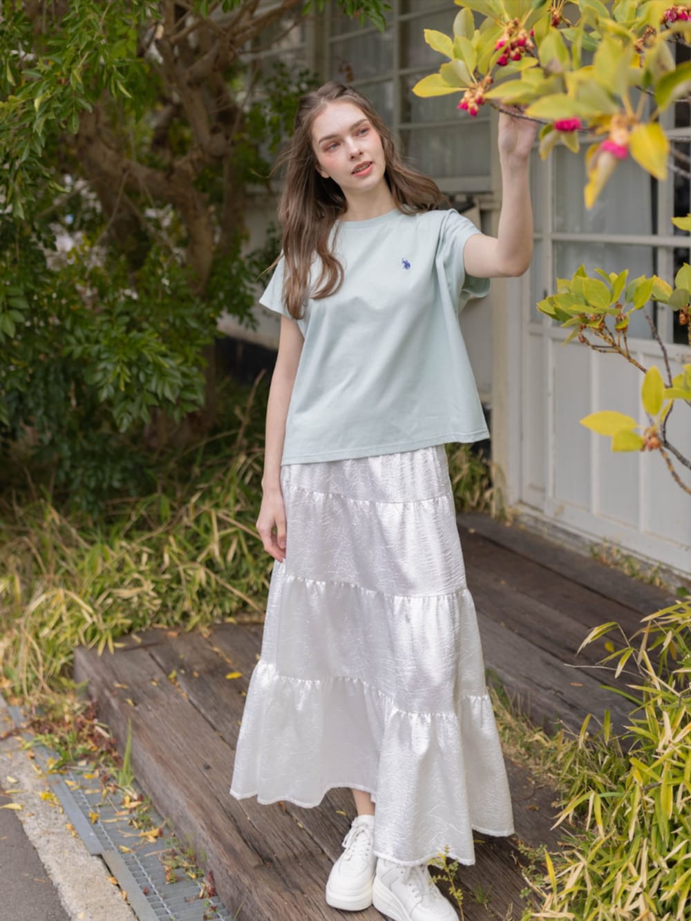 ホワイト系のスカート、グリーン系のTシャツ/カットソーを着用したレディースの夏コーディネートの2枚目の写真