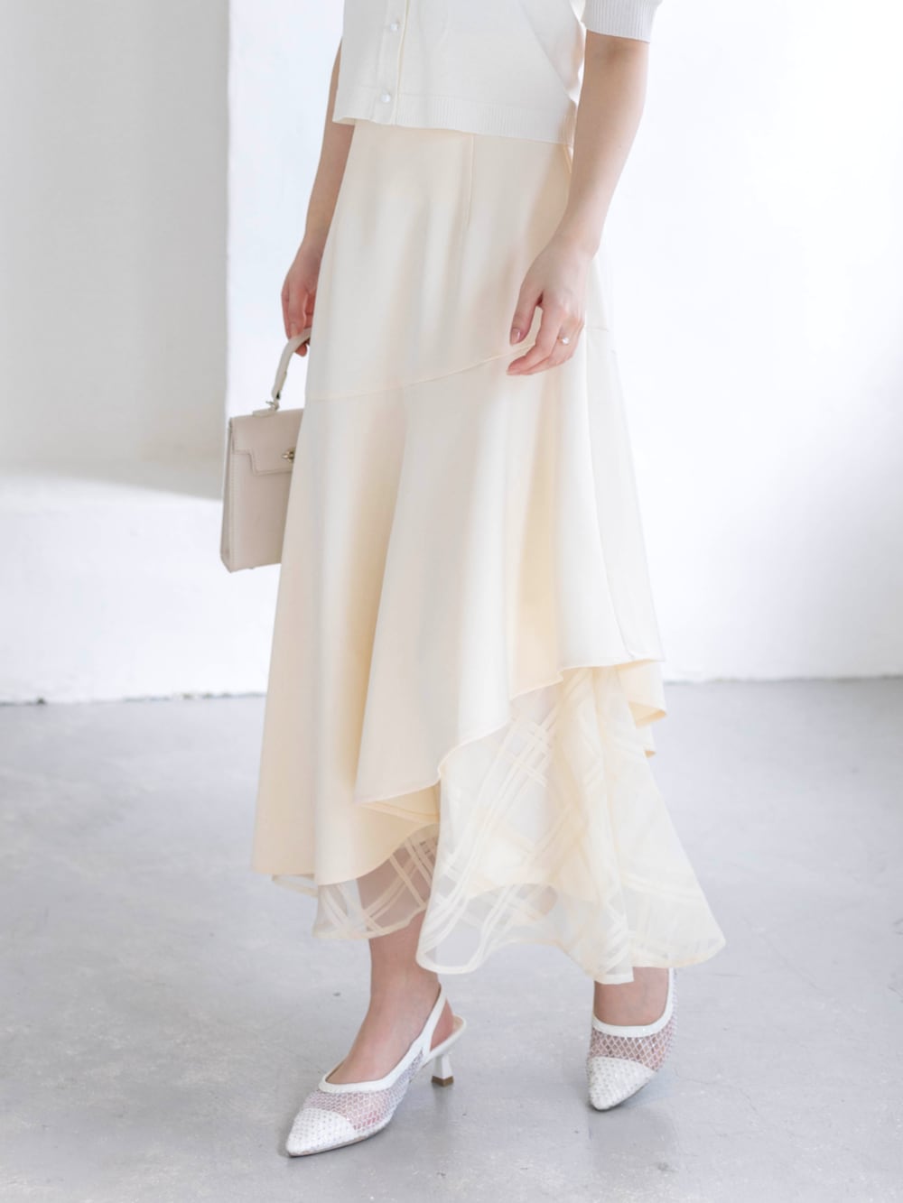 ホワイト系のスカート、ホワイト系のハンドバッグ、ホワイト系のパンプスを着用したレディースの春コーディネートの6枚目の写真