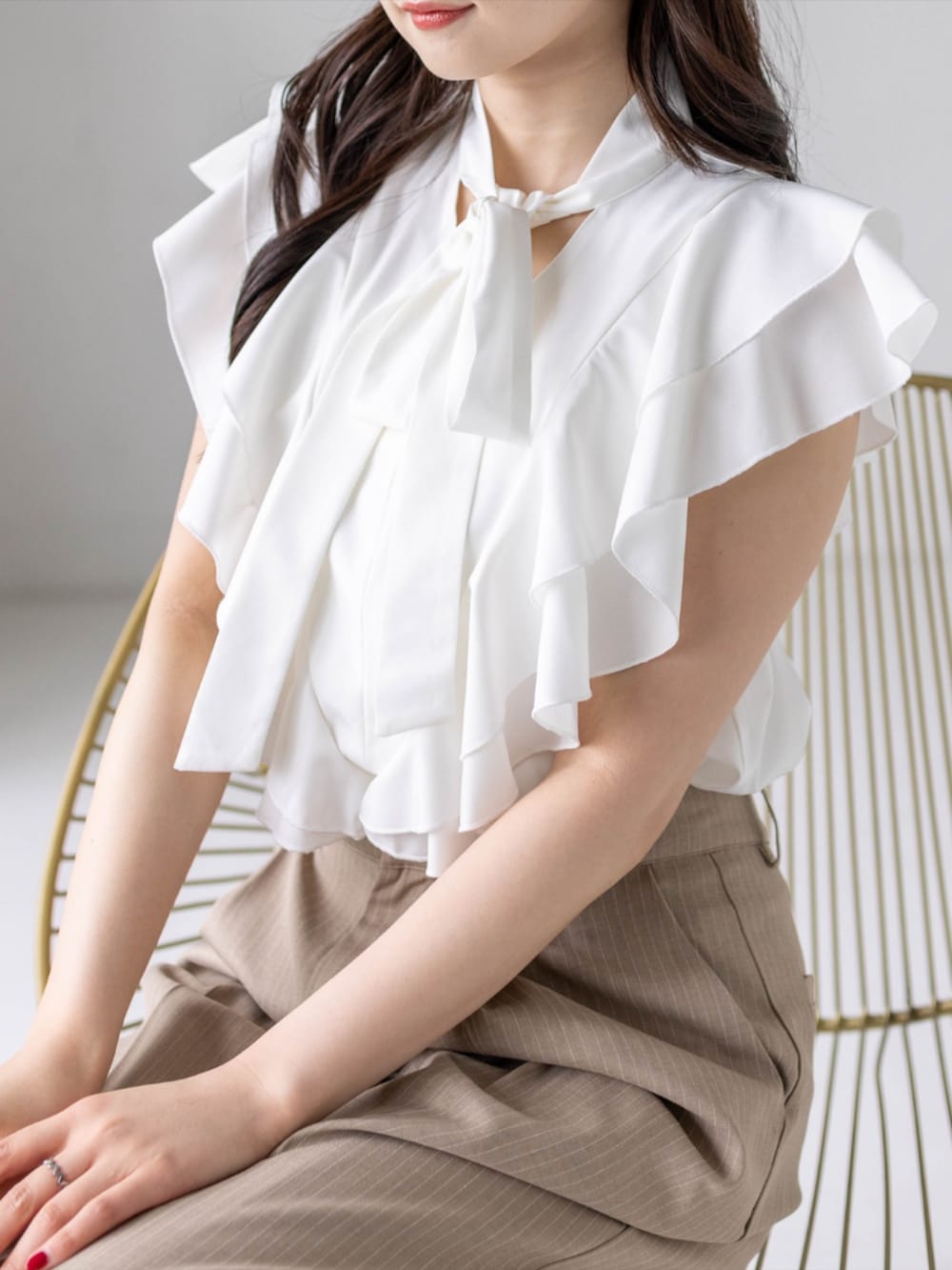ベージュ系のスラックス、ホワイト系のハンドバッグ、ホワイト系のパンプスを着用したレディースの夏コーディネートの8枚目の写真