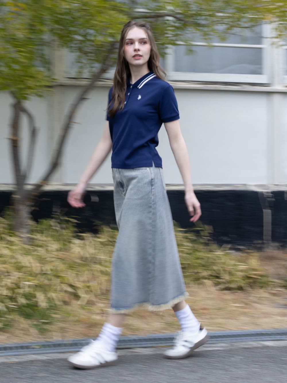 ホワイト系のスニーカー、ブルー系のデニムスカート、ブルー系のポロシャツを着用したレディースの夏コーディネートの3枚目の写真