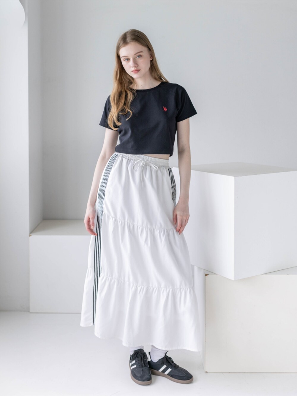 ブラック系のスニーカー、ホワイト系のスカート、ブラック系のTシャツ/カットソーを着用したレディースの夏コーディネートの2枚目の写真