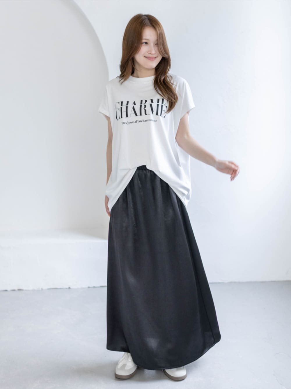 ホワイト系のスニーカー、ブラック系のスカート、ホワイト系のTシャツ/カットソーを着用したレディースの春コーディネートの2枚目の写真