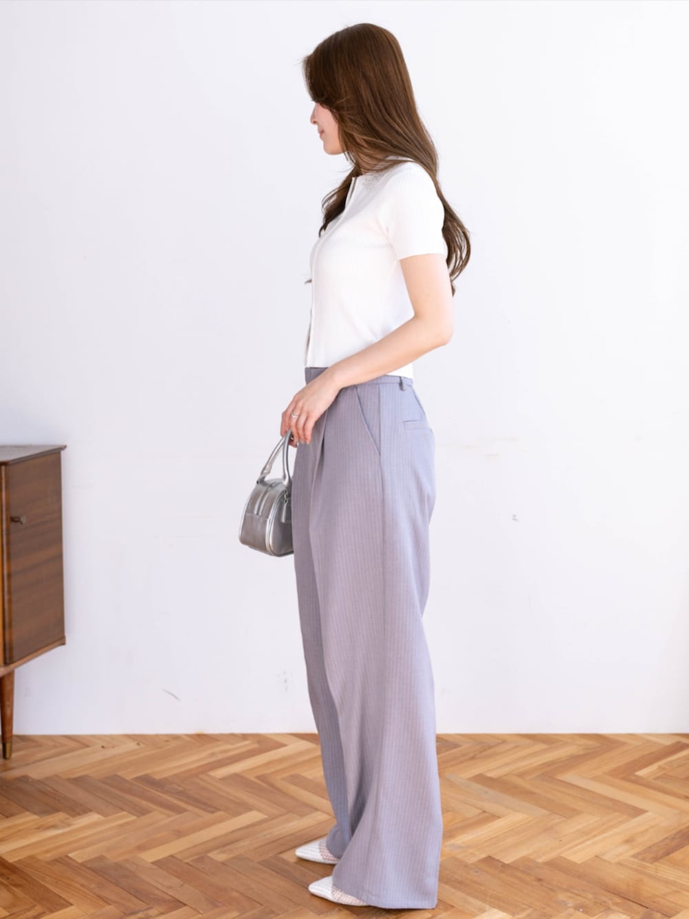 グレー系のスラックス、ホワイト系のパンプス、ホワイト系のニット/セーターを着用したレディースの春コーディネートの2枚目の写真