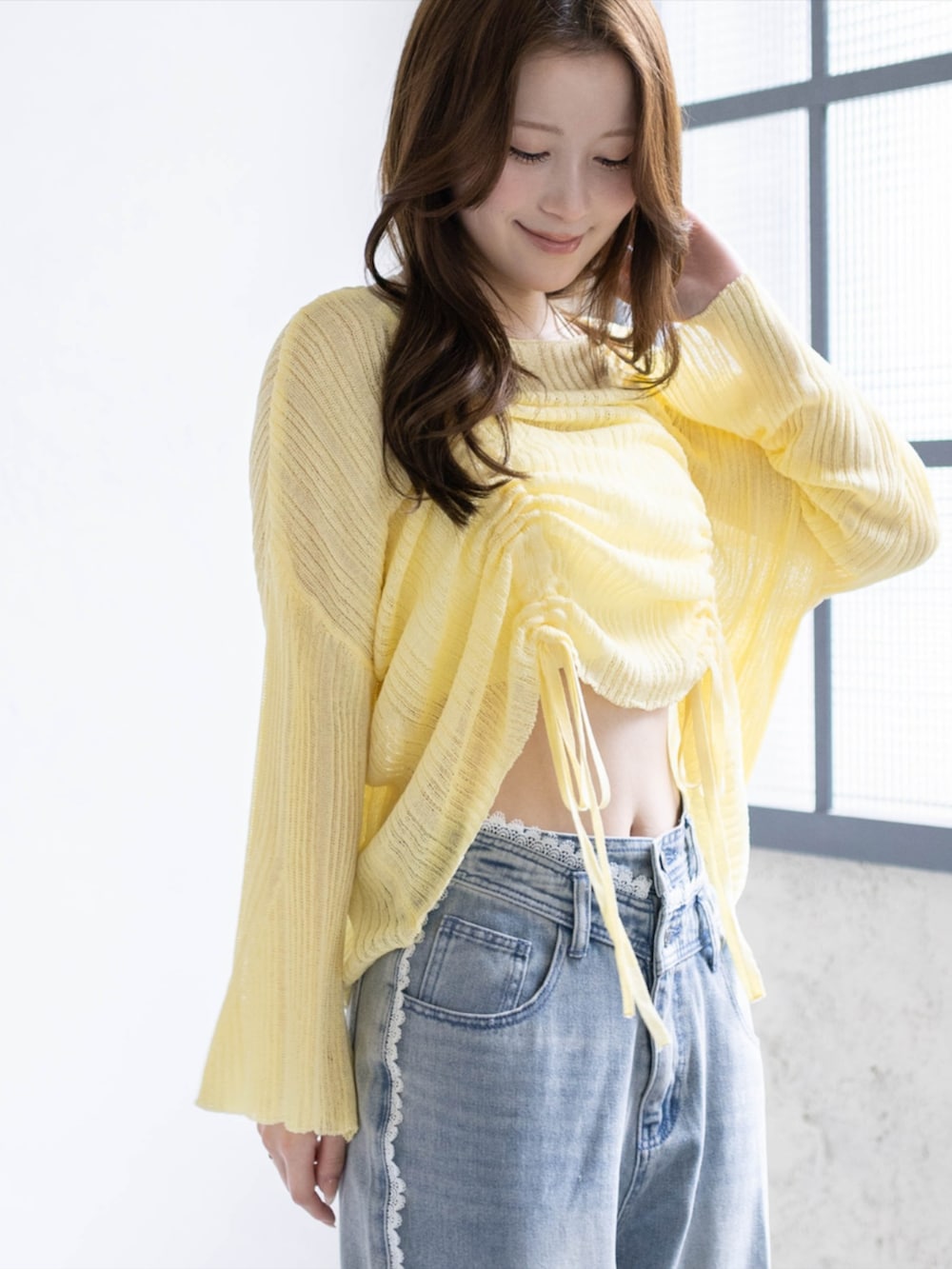 ブルー系のデニムパンツ、ホワイト系のパンプス、イエロー系のニット/セーターを着用したレディースの春コーディネートの4枚目の写真