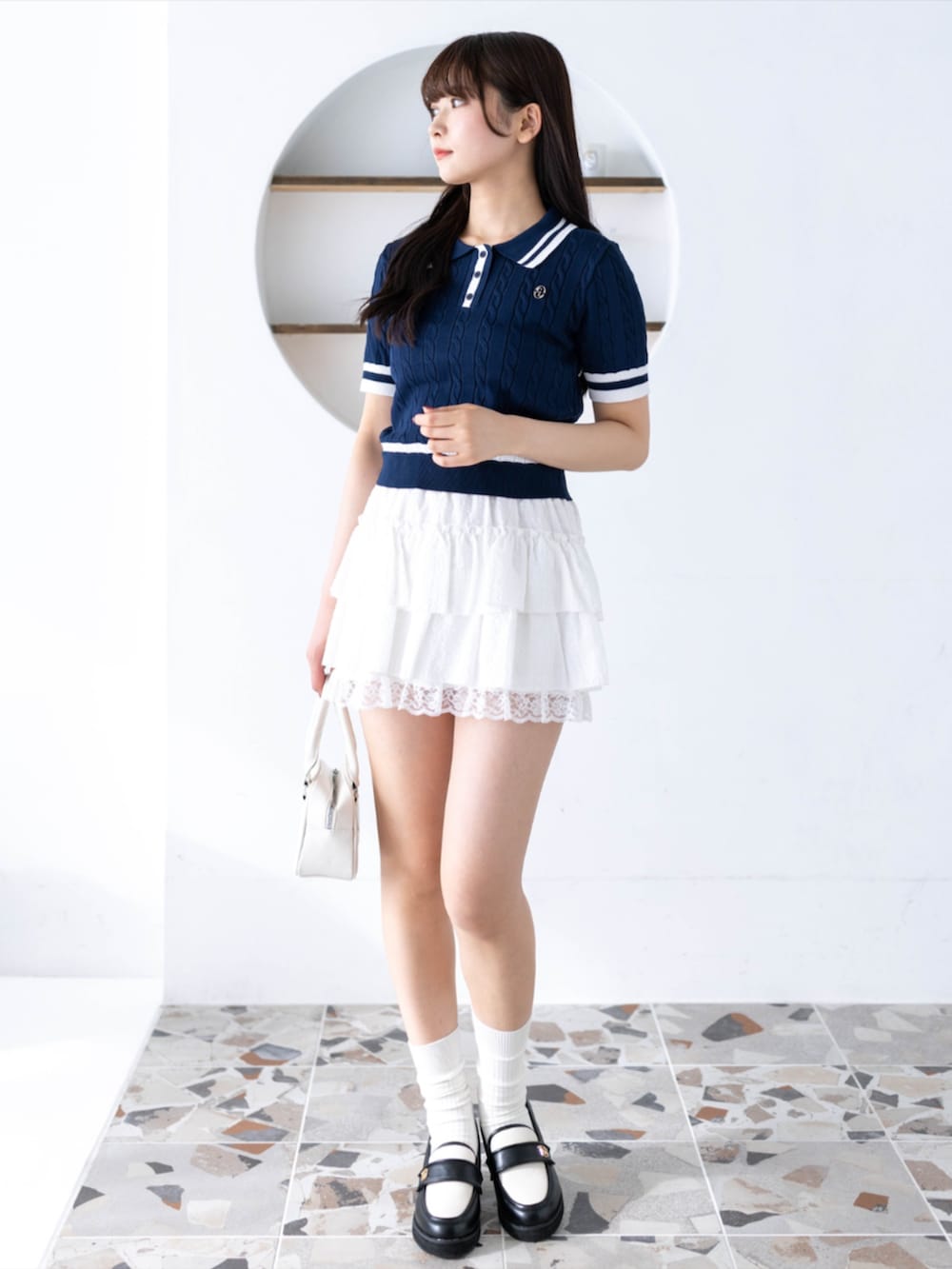 ホワイト系のハンドバッグ、ホワイト系のスカート、ブラック系のローファーを着用したレディースの春コーディネートの3枚目の写真