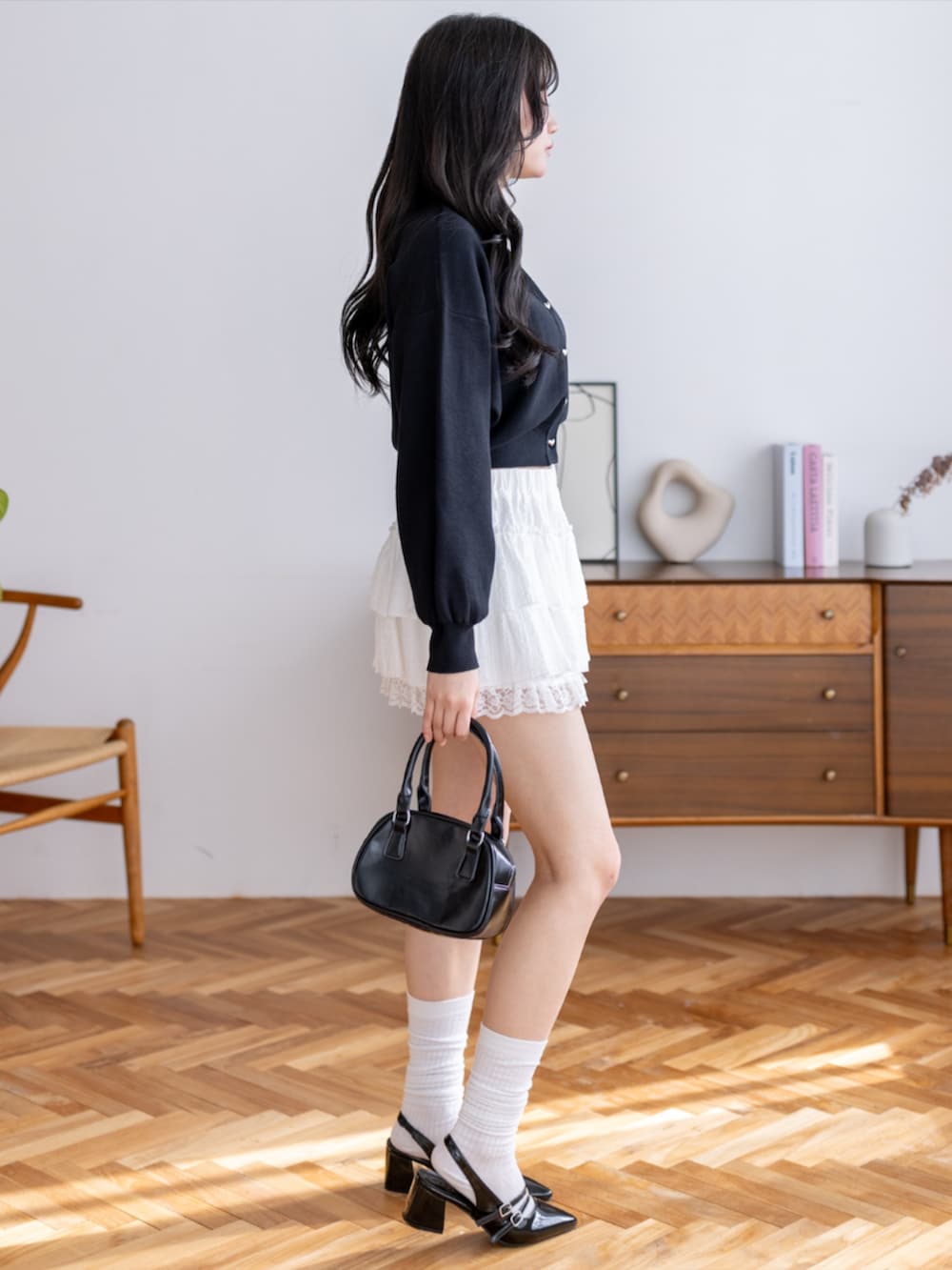 ブラック系のパンプス、ホワイト系のスカート、ブラック系のカーディガン/ボレロを着用したレディースの夏コーディネートの4枚目の写真