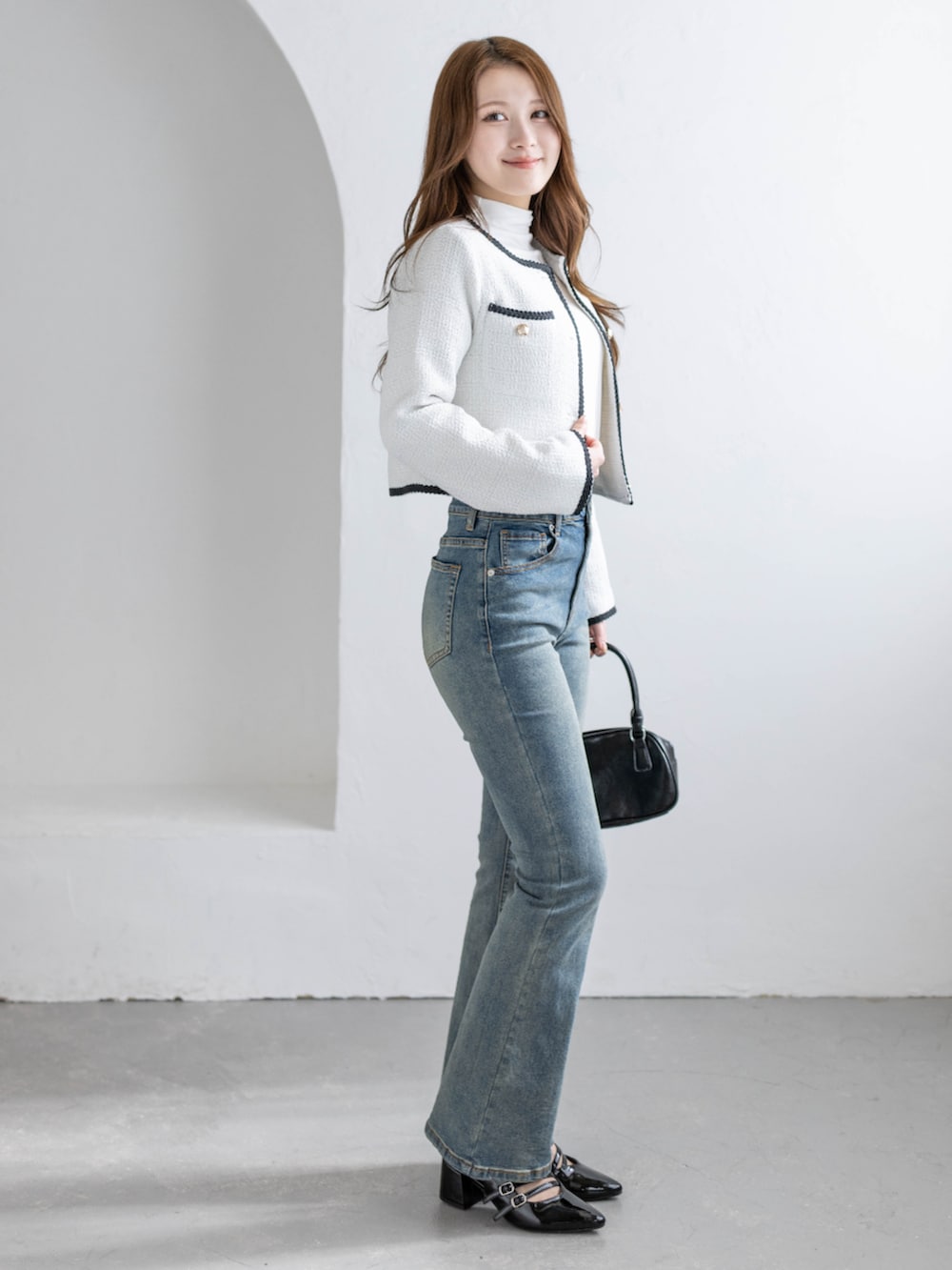 ブルー系のデニムパンツ、ブラック系のパンプス、ホワイト系のノーカラージャケットを着用したレディースの冬コーディネートの3枚目の写真