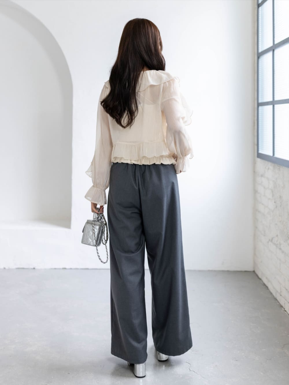 シルバー系のパンプス、ブラック系のスラックス、ベージュ系のシャツ/ブラウスを着用したレディースの春コーディネートの2枚目の写真